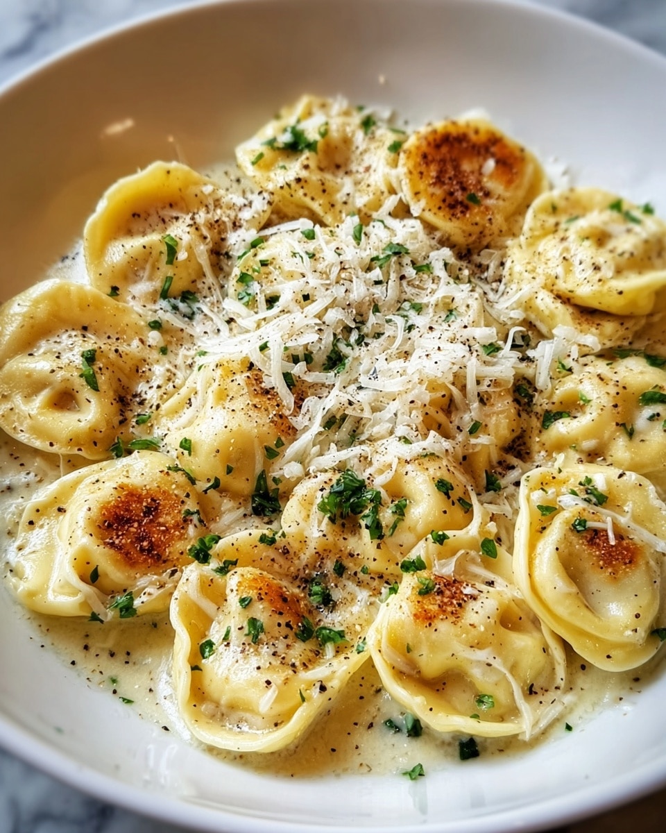 A white bowl filled with plump tortellini pasta that have a golden-brown, slightly crispy top layer. The pasta is coated with a creamy light yellow sauce that pools at the bottom. Bright green broccoli florets are mixed among the tortellini, adding a fresh color contrast. Small bits of green herbs and black pepper are sprinkled on top, with a light dusting of grated cheese giving a slightly textured layer above the pasta. The dish sits on a white marbled surface photo taken with an iphone --ar 4:5 --v 7