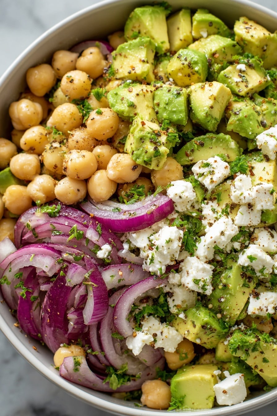 Chickpea Feta Avocado Salad, healthy chickpea salad, quick avocado salad, feta cheese salad, nutritious vegetarian salad - A close-up view of a white bowl filled with a colorful chickpea salad showing three main layers. The base layer is light beige chickpeas, round and smooth. The second layer consists of bright green avocado chunks, creamy and some with light grill marks. The third layer has rings of deep purple-red onion and white cubes of crumbly feta cheese. The salad is mixed with small pieces of fresh green parsley scattered evenly, all lightly seasoned with black pepper and chili flakes. The bowl sits on a white marbled surface, giving the image a fresh and clean look. photo taken with an iphone --ar 2:3 --v 7