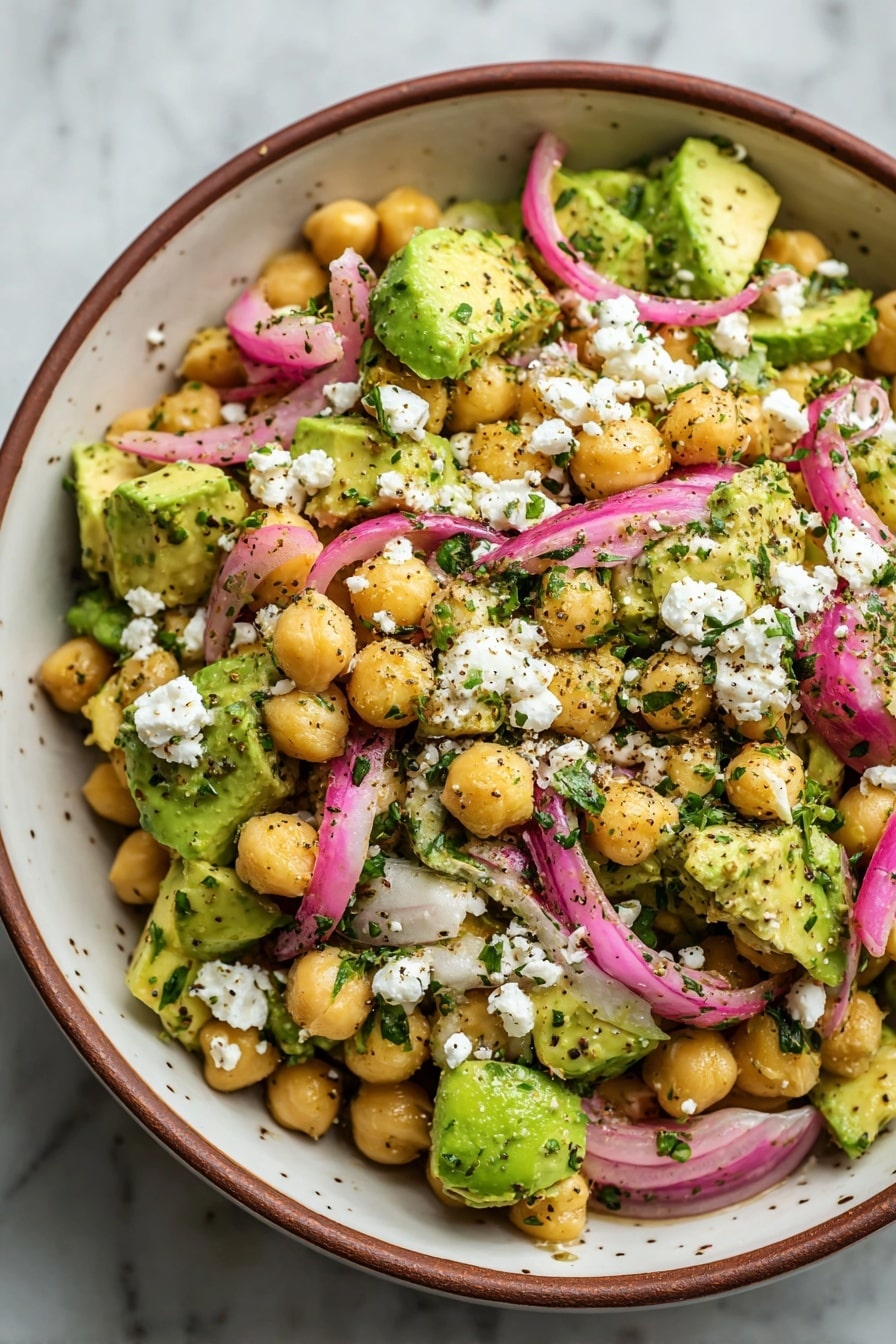 Chickpea Feta Avocado Salad, healthy chickpea salad, quick avocado salad, feta cheese salad, nutritious vegetarian salad - In a white bowl with a brown rim, there is a salad made of three main layers. The base layer consists of pale yellow chickpeas spread evenly, mixed with bright green avocado chunks that have a smooth texture. Scattered on top are thin slices of purple-red onion, adding a crunchy texture and vibrant color to the dish. The top layer is sprinkled with white crumbles of cheese and finely chopped green herbs, all lightly seasoned with black pepper specks, creating a fresh and colorful look. The background shows a white marbled surface. Photo taken with an iphone --ar 2:3 --v 7